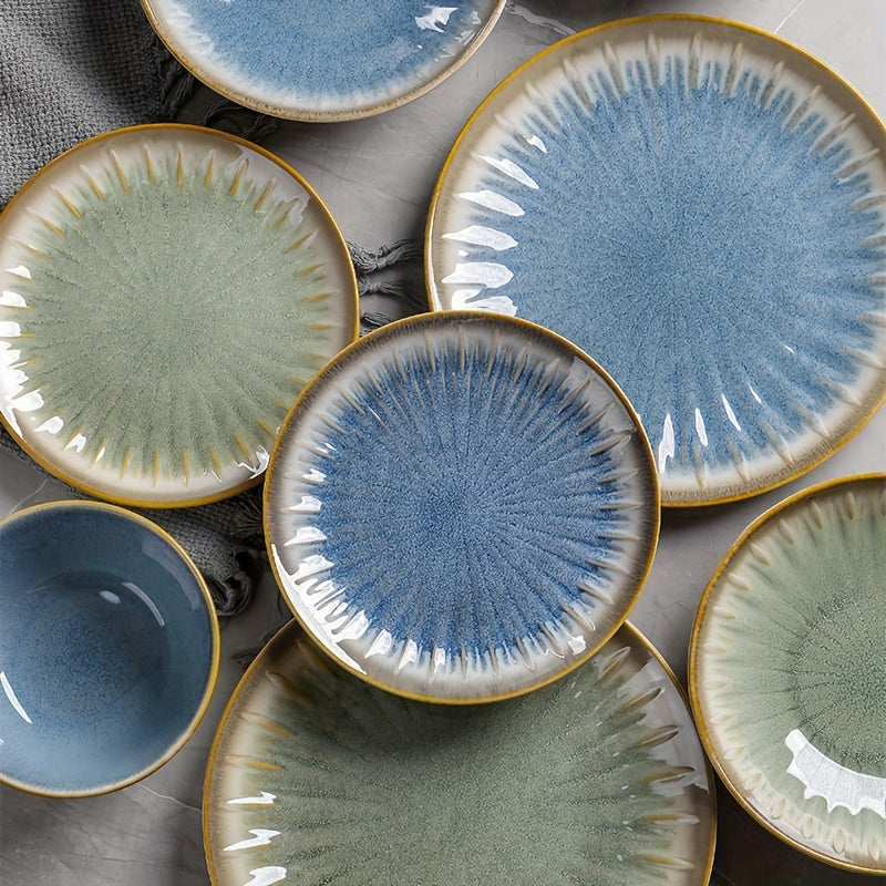 Set of ceramic plates with textured surfaces and gold rims on a gray surface.