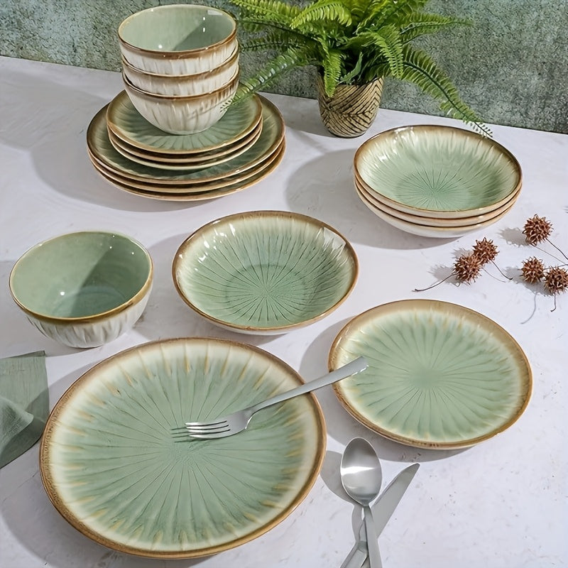 Set of green ceramic dinnerware with gold accents on a white tablecloth.