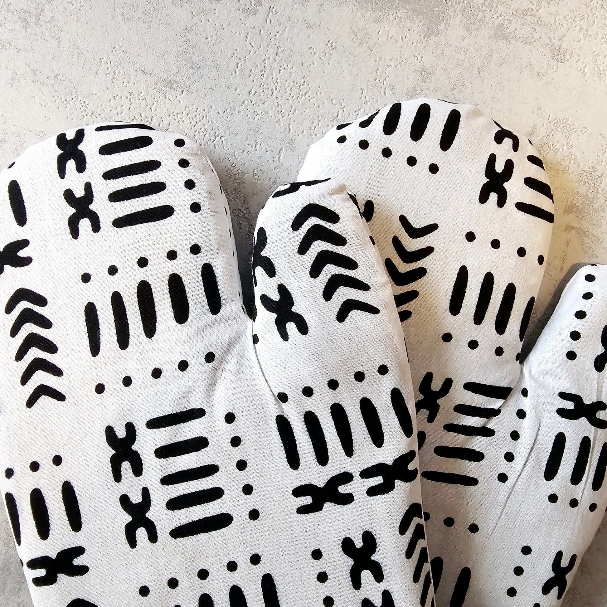 White oven mitts with black pattern on a light gray background